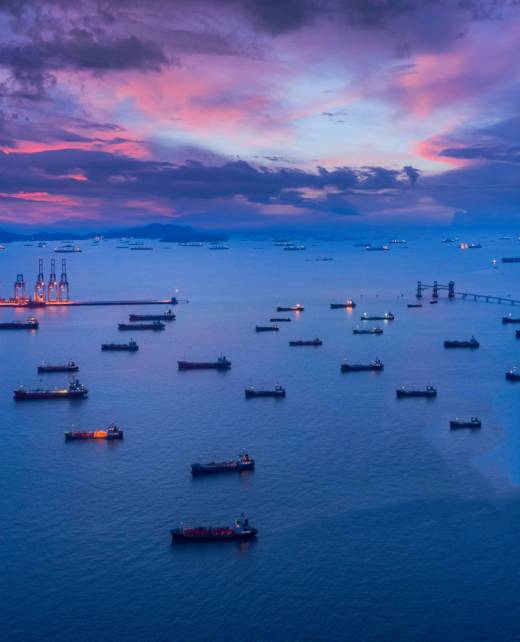 Aerial view Oil ship tanker park on the sea at dusk with beautiful sky waiting for load/unload oil from refinery for transportation.